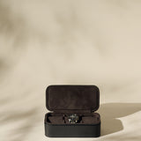 The TAWBURY Fraser 3 Watch Case - Black, with a soft interior, is shown on a beige background with gentle shadows—ideal for storing your watches during travel.