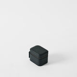 The TAWBURY Fraser 1 Watch Case in Midnight Black, crafted from textured leather, is a compact, rectangular case set against a white background—ideal for storing your watch while traveling.