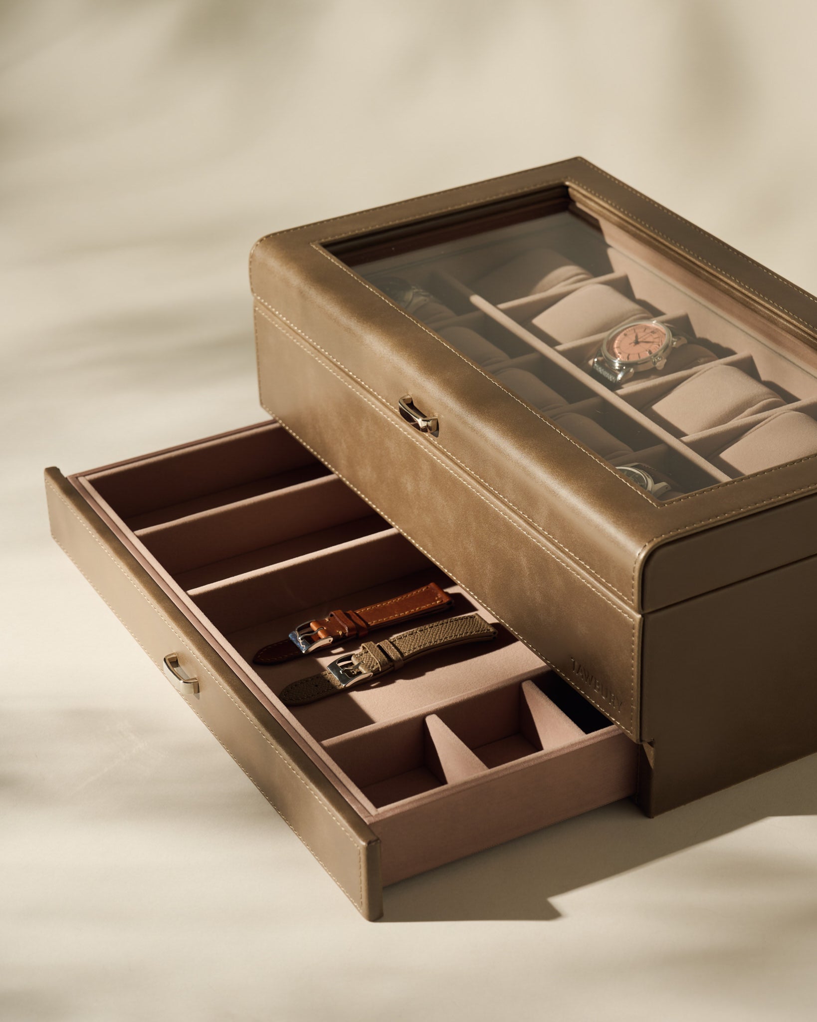 The TAWBURY Bayswater 12 Slot Watch Box with Storage in Taupe features a glass lid to showcase your watches, while the open drawer below offers extra compartments, making it the ideal stylish and practical organiser for your collection.