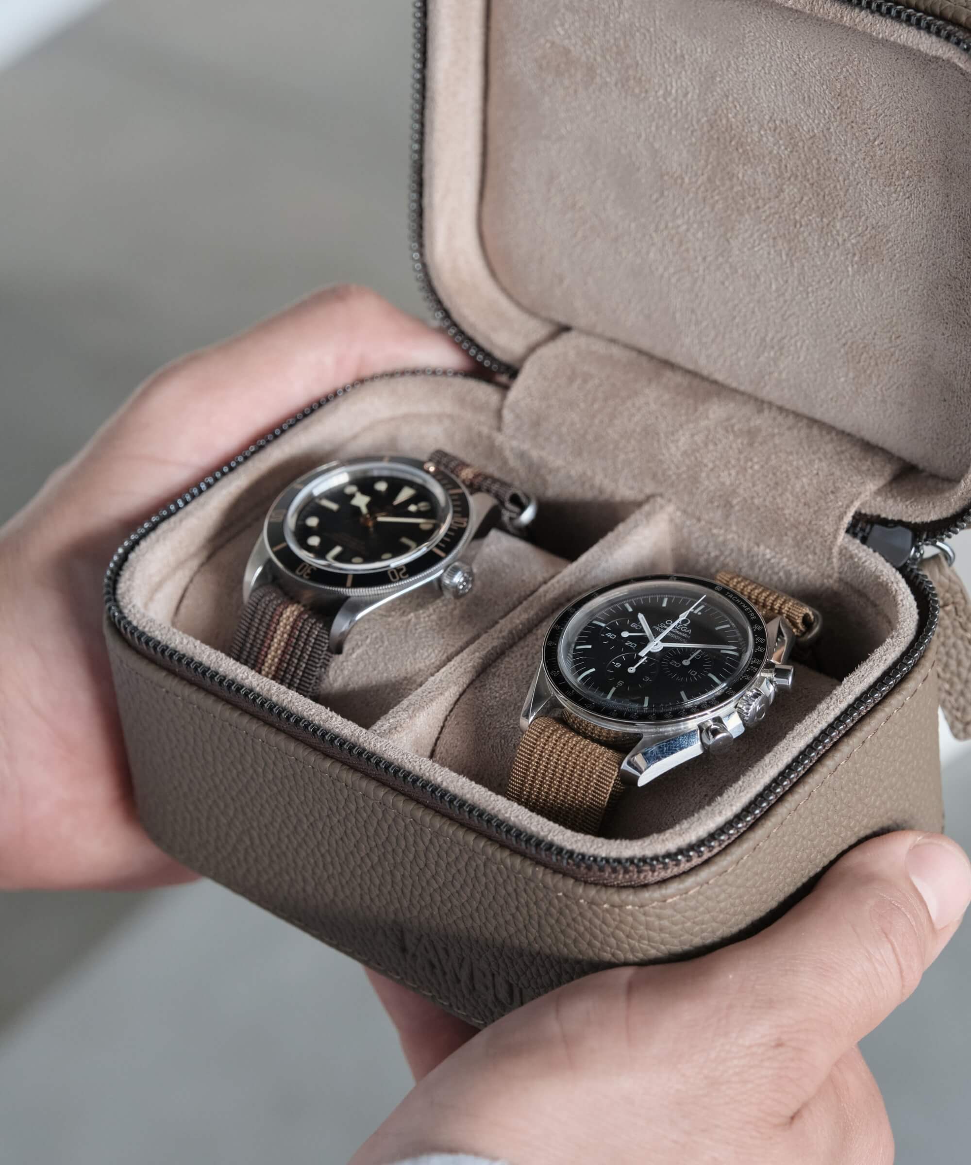 A watch lover displaying the TAWBURY Fraser 2 Watch Travel Case - Taupe, enhancing their travel experience with this stylish leather case that securely holds two watches.