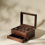 The TAWBURY Bayswater 8 Slot Watch Box with Storage in brown faux leather features a glass lid displaying two watches and a partially open lower drawer, revealing extra compartments for elegant watch organization.
