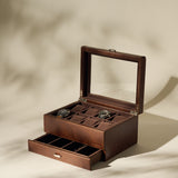 The TAWBURY Bayswater 8 Slot Watch Box with Storage in brown faux leather features a glass lid displaying two watches and a partially open lower drawer, revealing extra compartments for elegant watch organization.