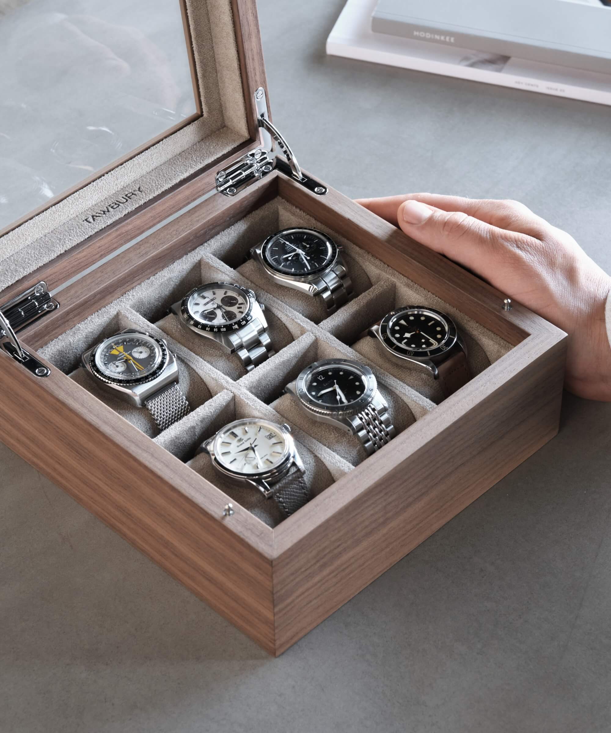 A watch enthusiast is holding a TAWBURY Grove 6 Slot Watch Box with Glass Lid - Walnut.
