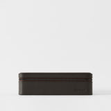 The Fraser 8 Watch Case by TAWBURY, in espresso brown leather with a zipper, sits on a plain white background and features "TAWBURY" embossed on the lower right corner.