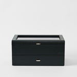 The TAWBURY Bayswater 24 Slot Watch Box with Drawer in Midnight Black features a rectangular design, two drawers, and a transparent glass lid for elegant watch display, shown against a plain white background.