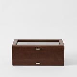 The TAWBURY Bayswater 12 Slot Watch Box with Storage in Chestnut Brown features a glass top and metal handle, ideal for storing and displaying watches, shown against a plain white background.