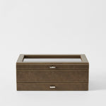 The TAWBURY Bayswater 12 Slot Watch Box with Storage in Driftwood Taupe features a closed glass top and two silver handles, displayed against a plain white background.