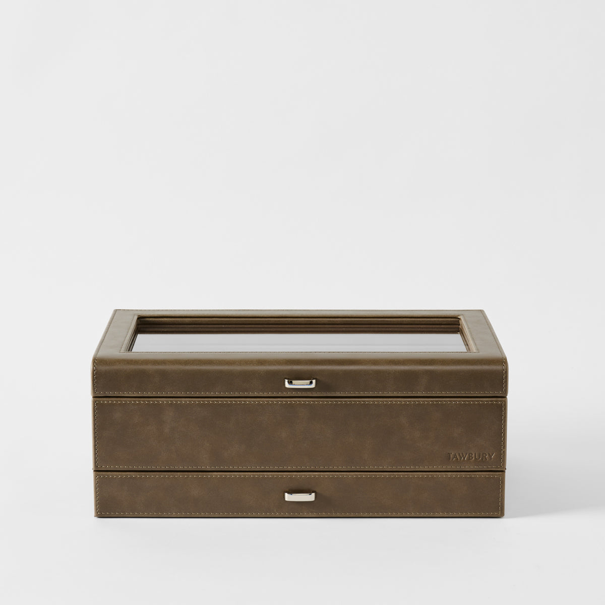 The TAWBURY Bayswater 12 Slot Watch Box with Storage in Driftwood Taupe features a closed glass top and two silver handles, displayed against a plain white background.