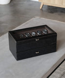 A black TAWBURY Bayswater 24 Slot Watch Box with Drawer on a table next to a coffee table.