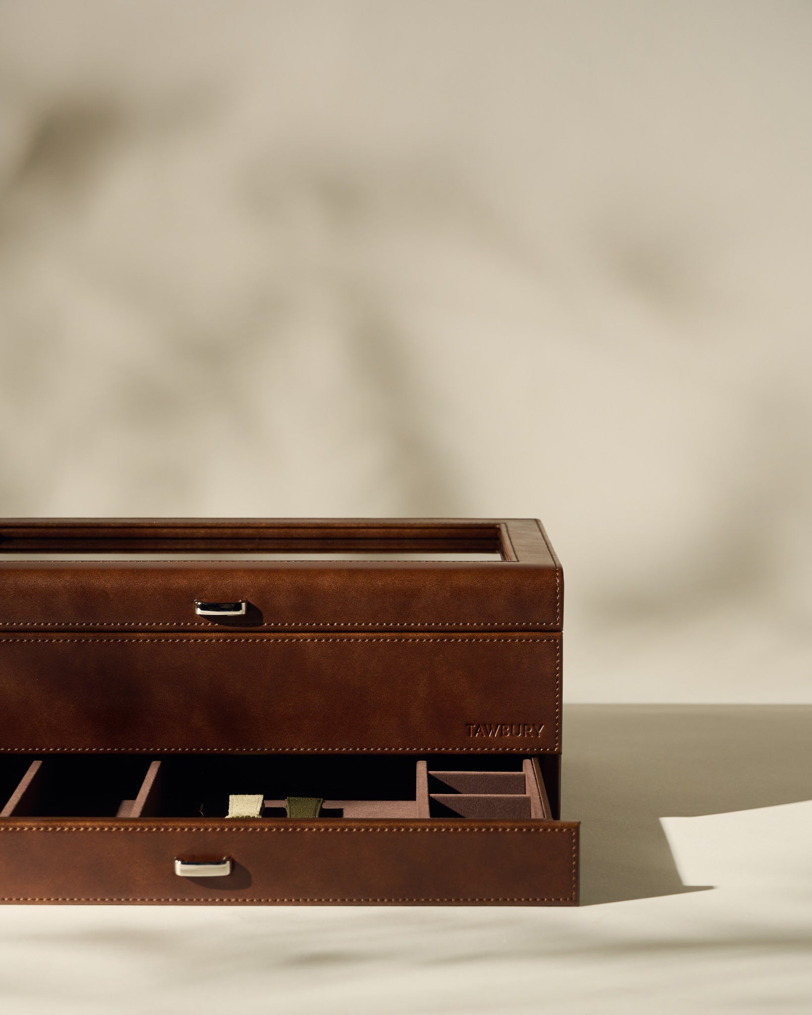 The TAWBURY Bayswater 12 Slot Watch Box with Storage in brown, featuring organized compartments and a partially open drawer, is displayed on a neutral background.