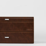 A close-up of the TAWBURY Bayswater 24 Slot Watch Box with Drawer in brown leather, featuring metal handles and “TAWBURY” embossed on the side, set against a plain white background.