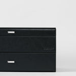 The Bayswater 24 Slot Watch Box with Drawer in black/charcoal by TAWBURY features silver handles and an embossed brand name, offering stylish watch storage, shown on a plain white background.