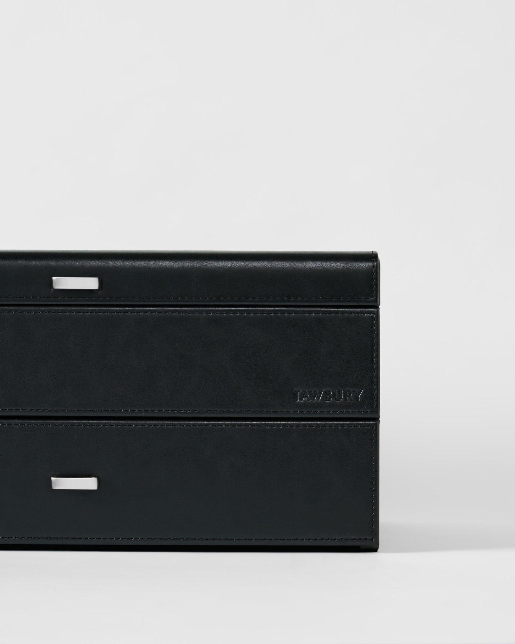 The Bayswater 24 Slot Watch Box with Drawer in black/charcoal by TAWBURY features silver handles and an embossed brand name, offering stylish watch storage, shown on a plain white background.