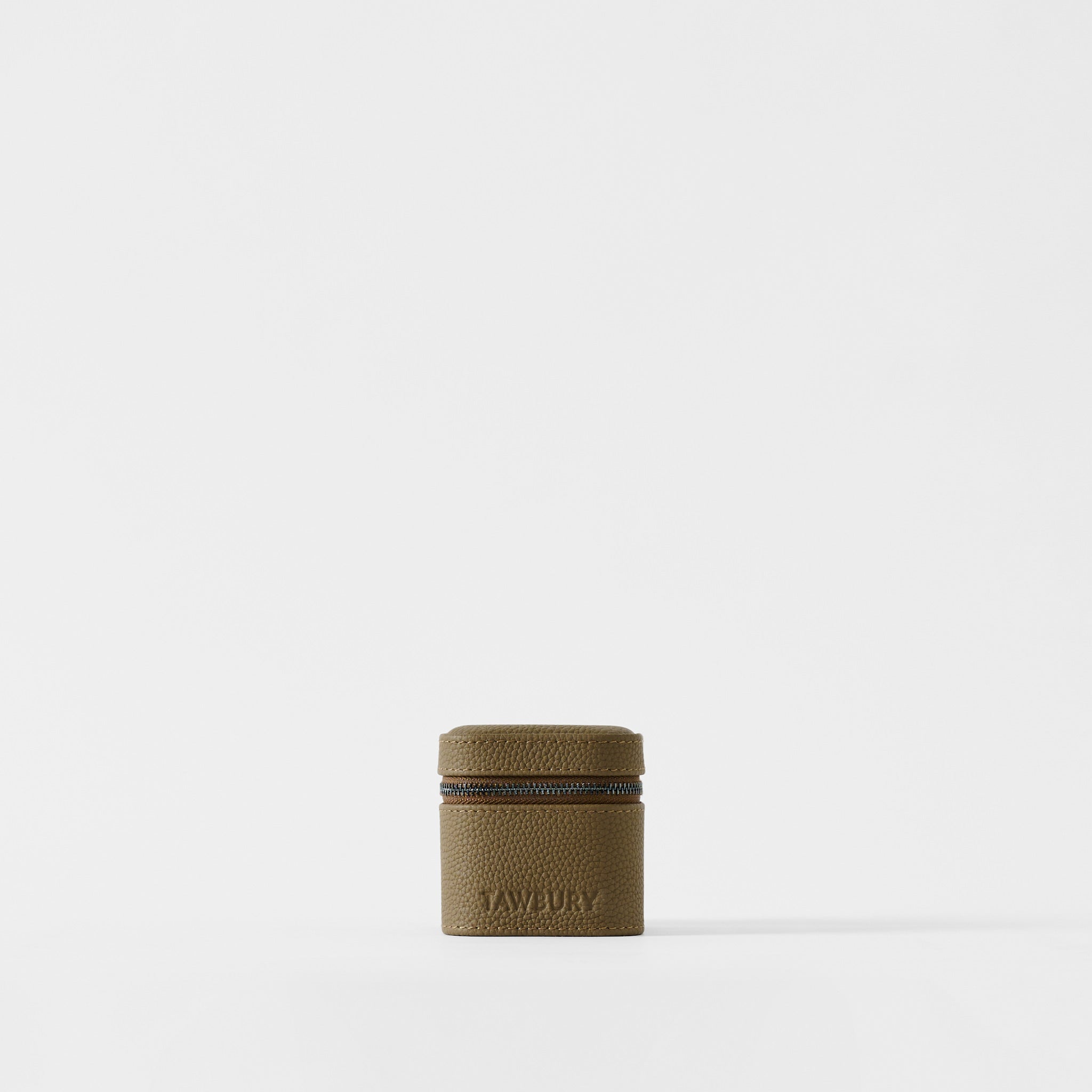 The Fraser 1 Watch Case by TAWBURY is a compact, square, truffle taupe leather case with a zipper and "TAWBURY" embossed on the front—ideal for travel watch storage—shown against a plain white background.