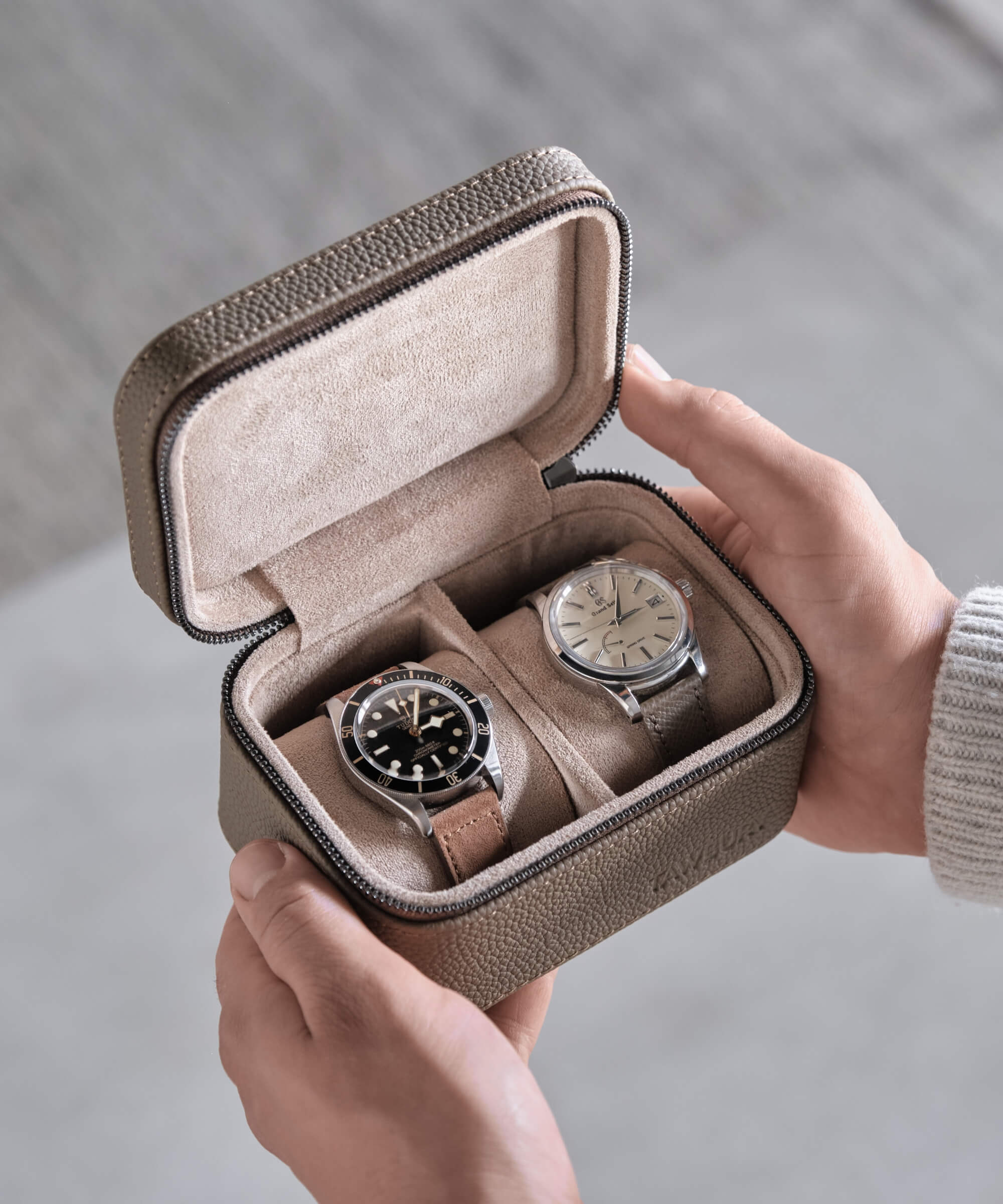 A watch lover's travel experience captured in a TAWBURY Fraser 2 Watch Travel Case - Taupe, featuring a person holding two watches in the leather case.