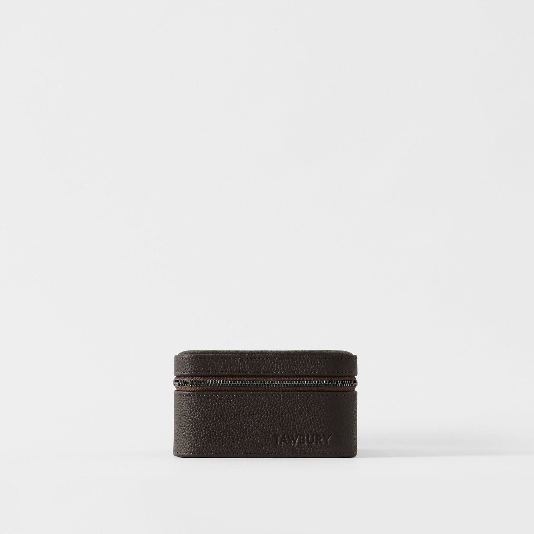 The Fraser 2 Watch Case by TAWBURY is a small, rectangular case in espresso brown leather with a zippered closure and "TAWBURY" embossed on the front, shown against a plain white background.
