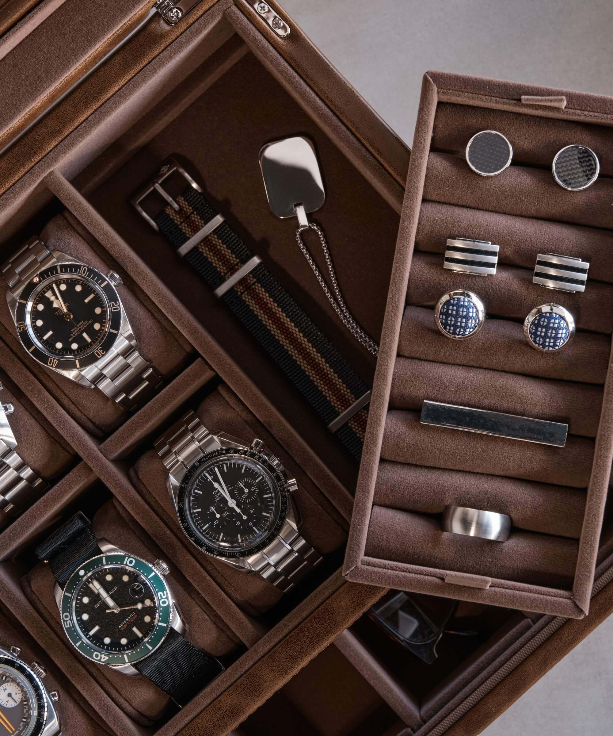 The TAWBURY Bayswater 6 Watch Jewellery Box - Brown is a stylish, vegan leather brown box that is perfect for watch enthusiasts. It is filled with an assortment of watches, cufflinks, and other accessories.