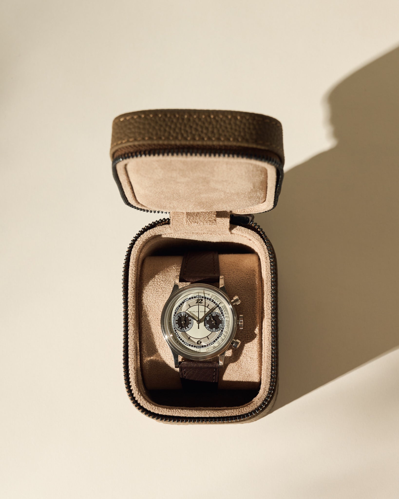 A silver chronograph wristwatch with a dark leather strap is displayed in an open TAWBURY Fraser 1 Watch Case - Taupe on a light background.