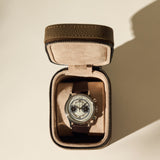 A silver chronograph wristwatch with a dark leather strap is displayed in an open TAWBURY Fraser 1 Watch Case - Taupe on a light background.