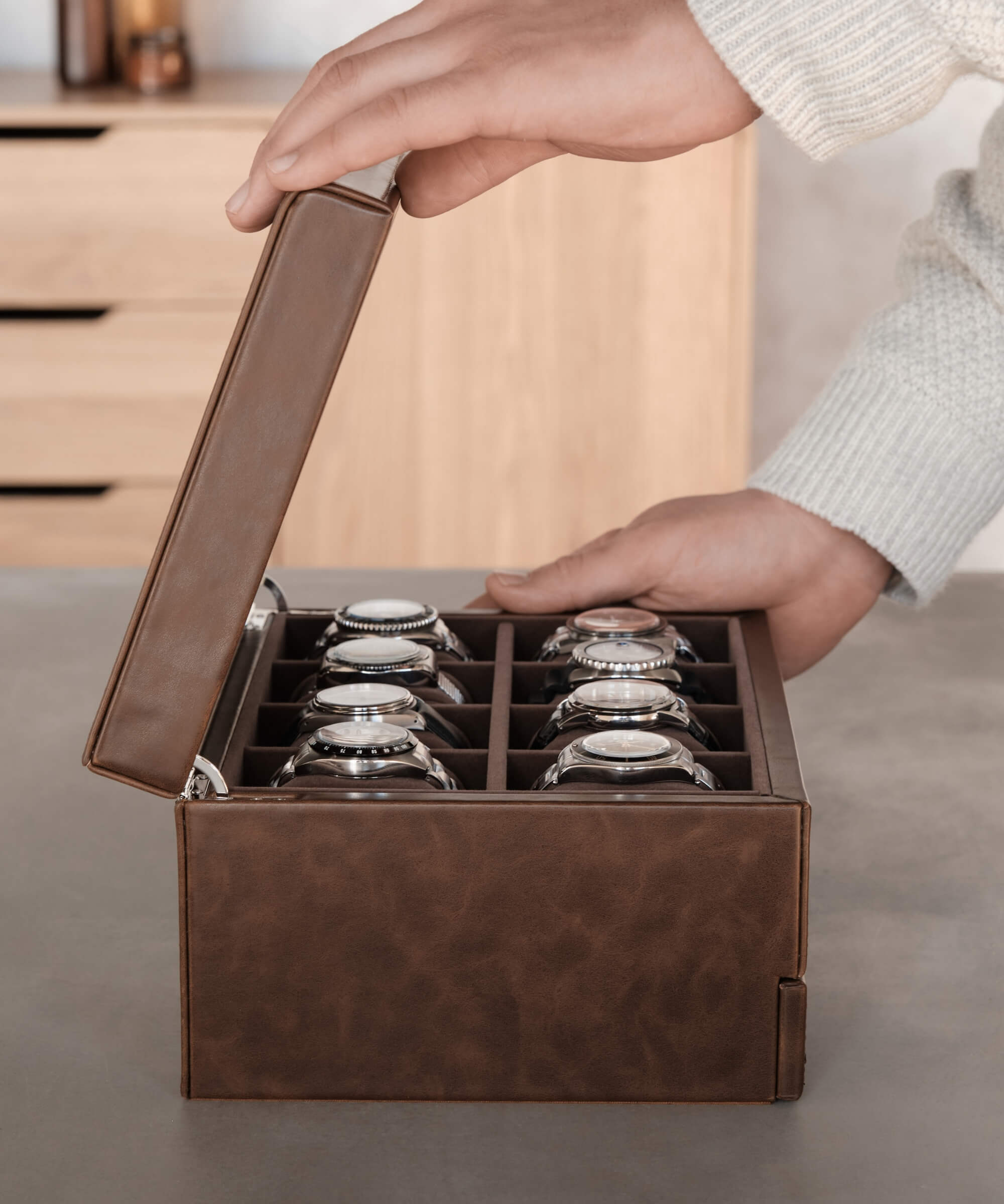 A person holding a TAWBURY Bayswater 8 Slot Watch Box with Drawer - Brown filled with wrist watches.