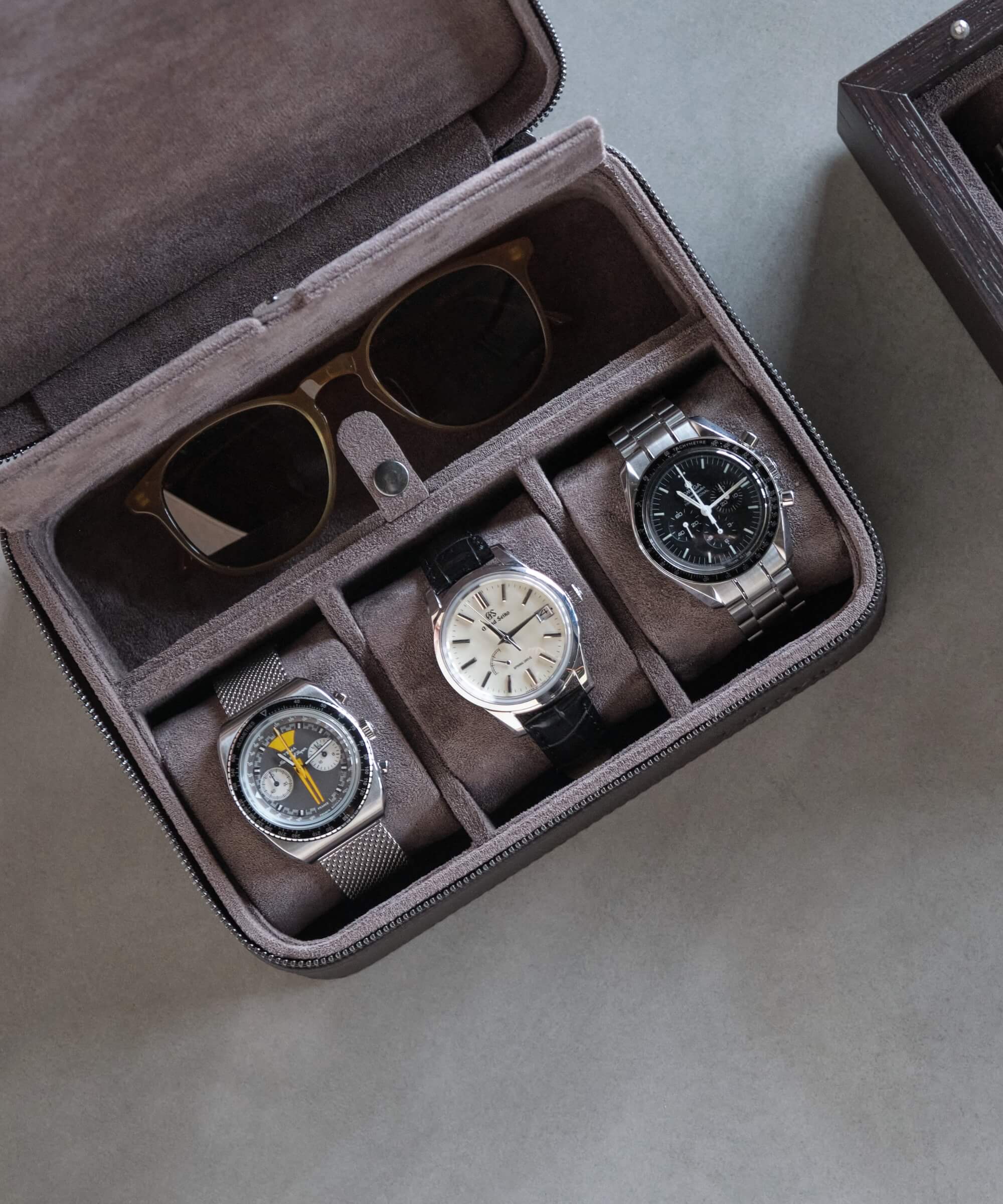 A TAWBURY Fraser 3 Watch Travel Case with Storage - Brown, a watch lover's collection of three elegant timepieces, neatly arranged in the stylish leather case on a table.