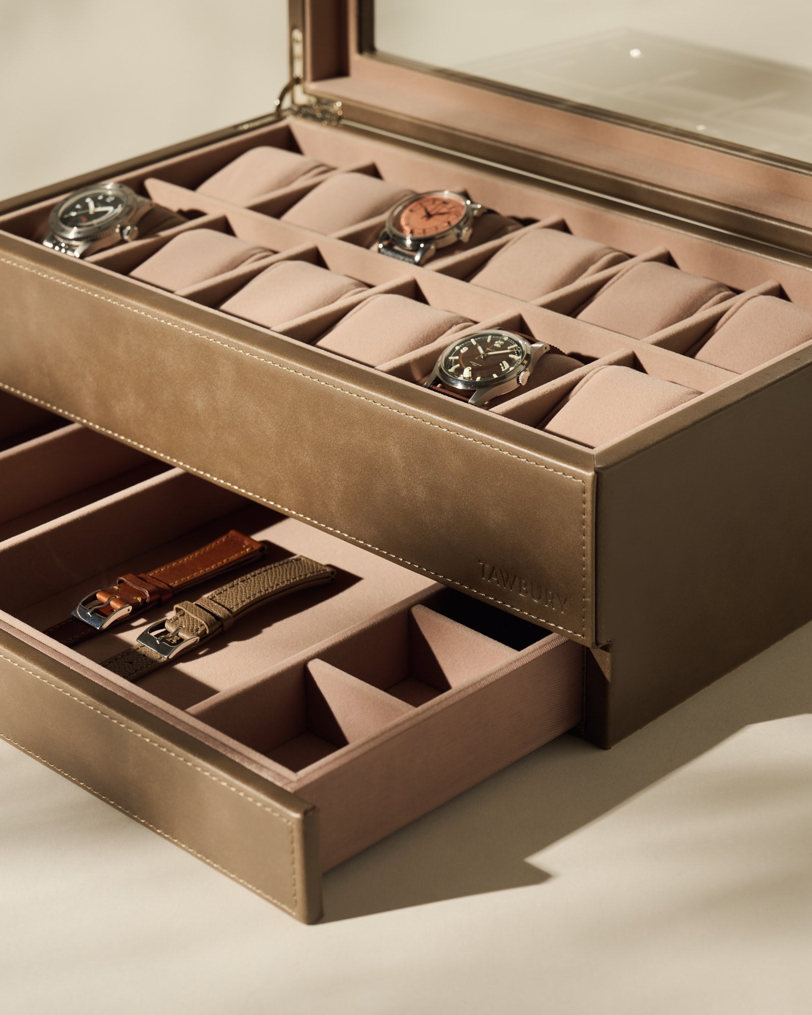 The TAWBURY Bayswater 12 Slot Watch Box with Storage in taupe features a glass lid for displaying your watches and an open lower drawer for storing interchangeable straps and accessories.