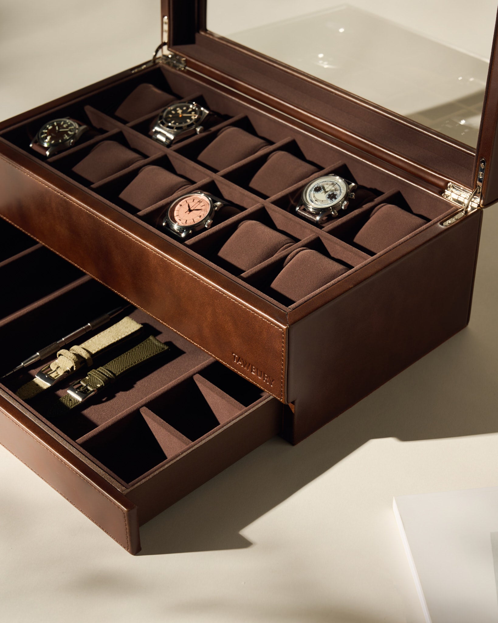 The TAWBURY Bayswater 12 Slot Watch Box with Storage in brown features multiple compartments, holds up to 12 wristwatches, and includes a lower drawer for watch straps.