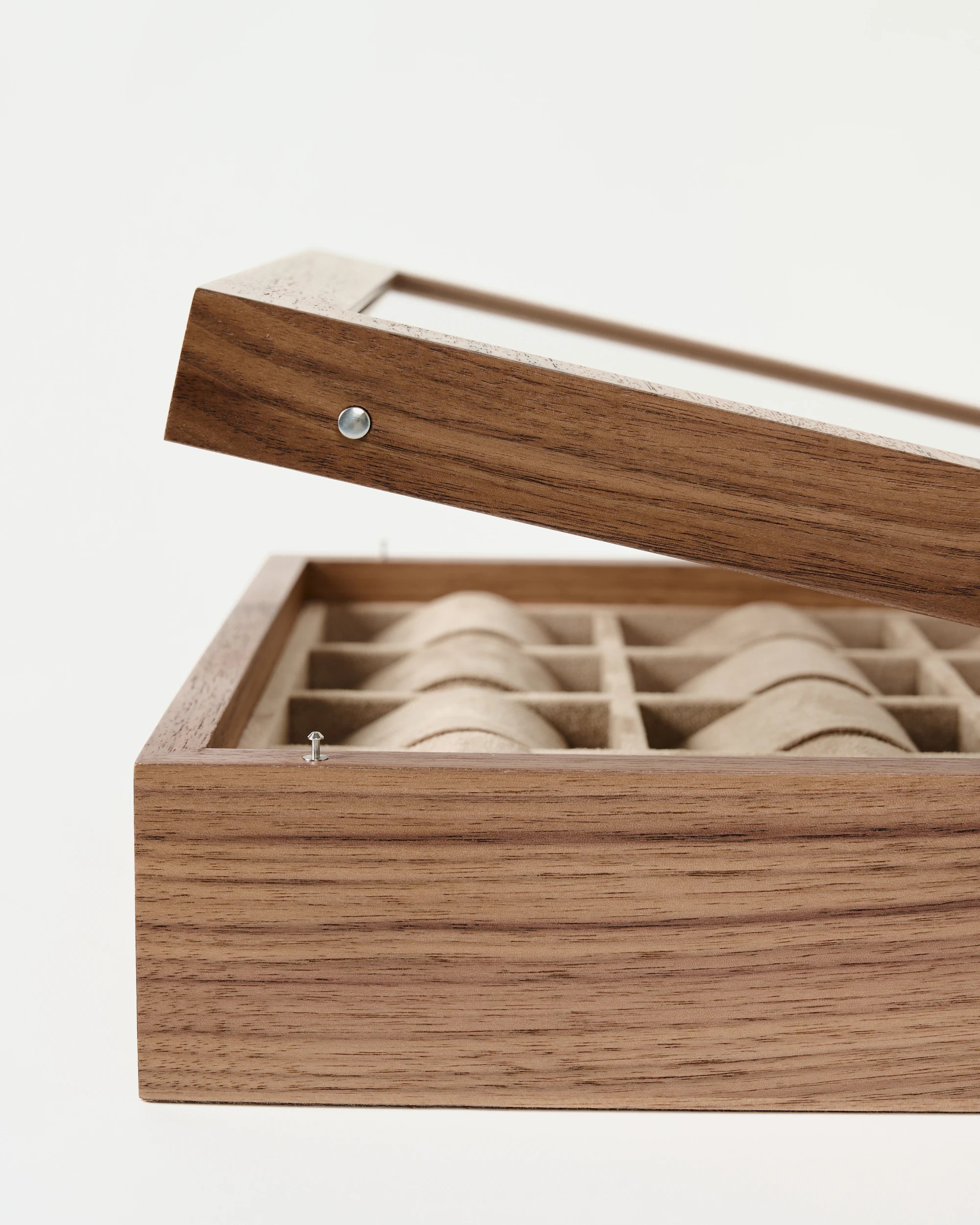 The TAWBURY Grove 12 Slot Wooden Watch Box in light walnut features a glass lid, shown slightly open to reveal beige fabric-lined divided compartments.