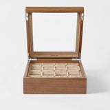 The TAWBURY Grove 12 Slot Wooden Watch Box in classic walnut wood features a glass lid and beige cushioned compartments, making it the ideal display case for organizing your watch or jewelry collection.