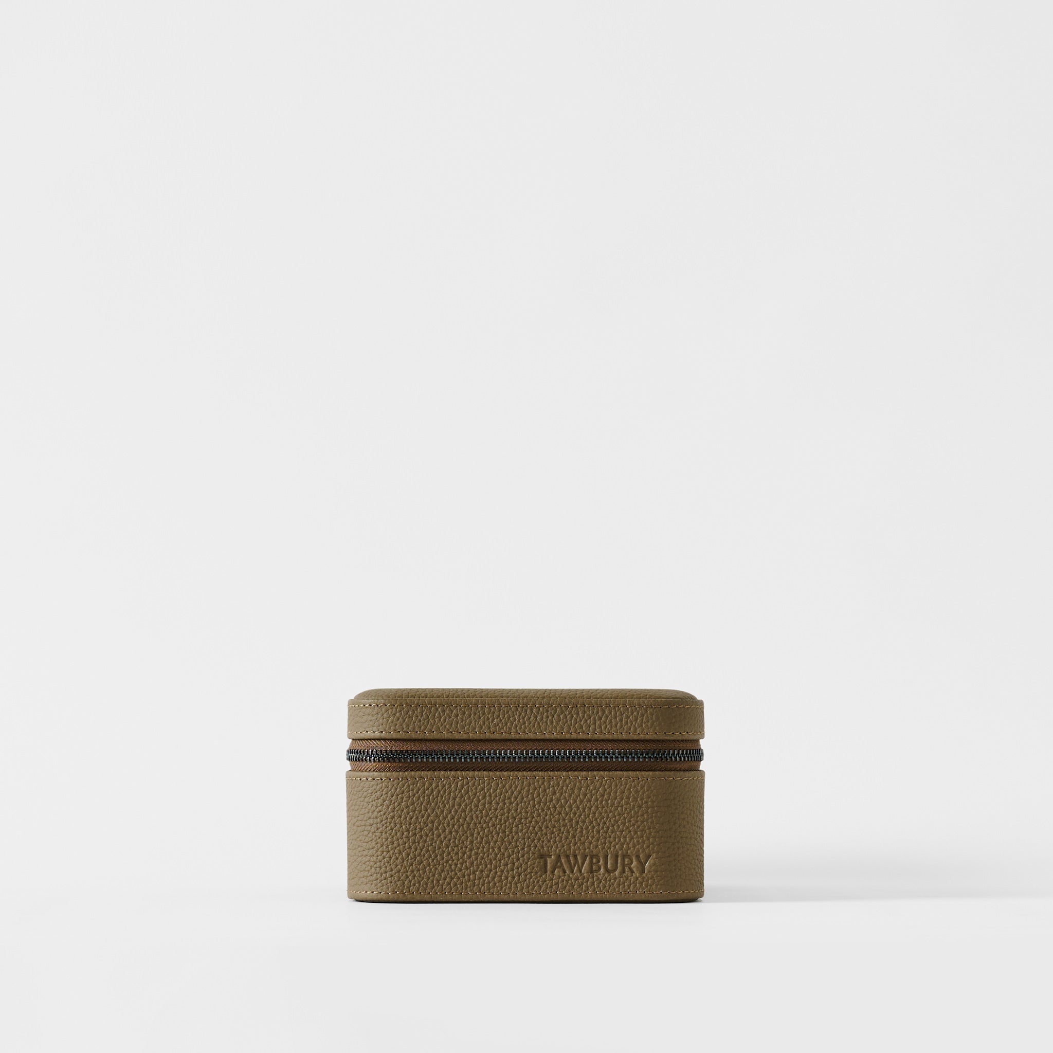 The Fraser 2 Watch Case - Truffle Taupe by TAWBURY is a small, rectangular, textured brown travel case with a zippered closure on a white background, featuring "TAWBURY" embossed on the front.