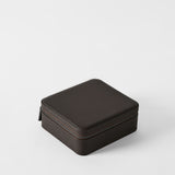 The TAWBURY Fraser 6 Watch Case in espresso brown leather features a square, textured design with a zipper, securely storing up to 6 watches. Shown closed on a plain white background.