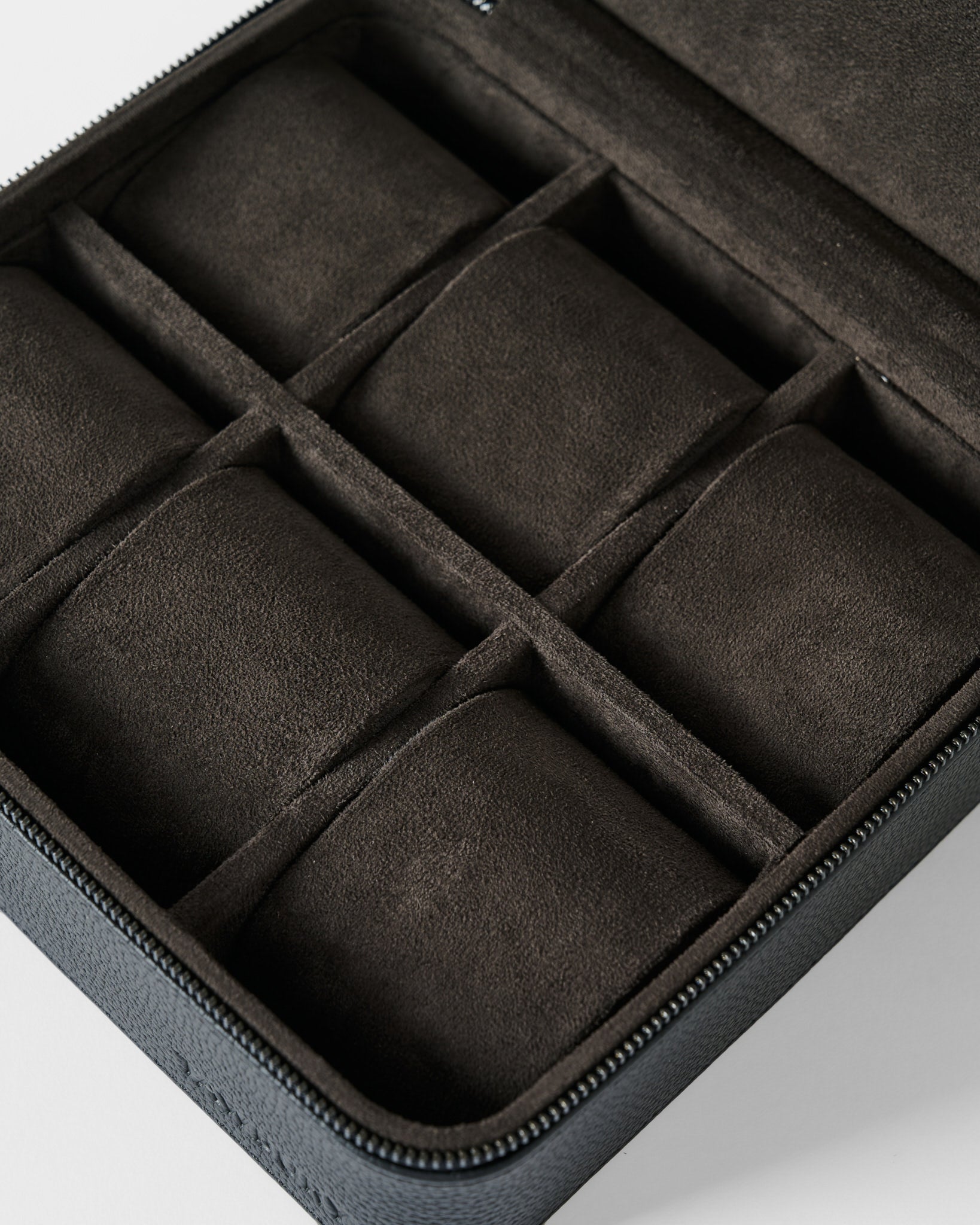 A close-up of the TAWBURY Fraser 6 Watch Case - Black, featuring six suede-lined compartments for organizing and storing watches or jewelry.
