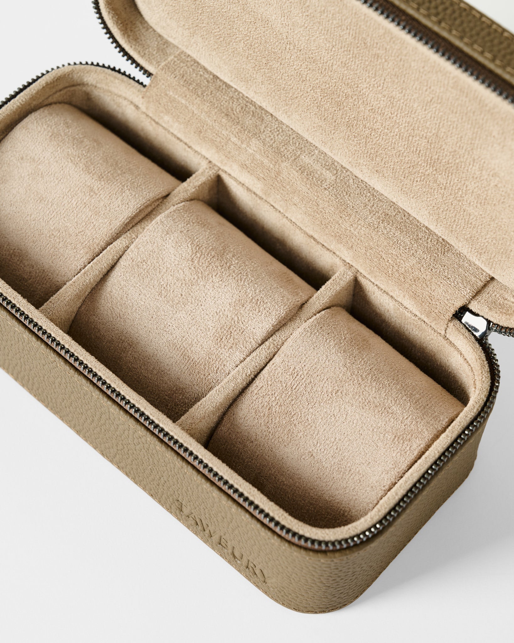The TAWBURY Fraser 3 Watch Case in taupe is a rectangular leather travel case with a zip closure, beige suede interior, and three padded sections for organizing your watches.