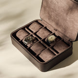 The TAWBURY Fraser 8 Watch Case in brown suede leather displays two wristwatches in separate compartments, with several empty slots for organized storage and elegant protection of your collection.