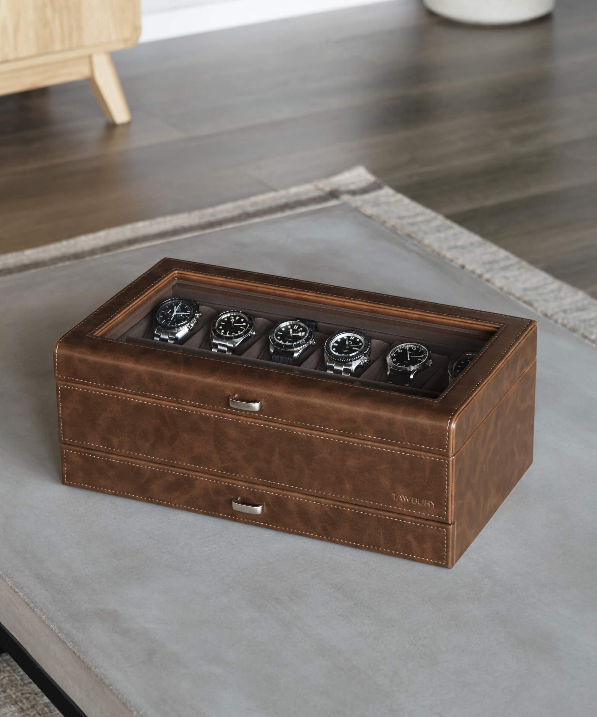A TAWBURY Bayswater 12 Slot Watch Box with Drawer - Brown, designed for timepieces, sitting on top of a table.
