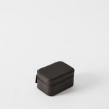The TAWBURY Fraser 2 Watch Case in espresso brown features a small, rectangular design with textured leather and a zippered closure, displayed on a plain white background.