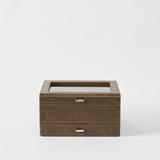 The Bayswater 8 Slot Watch Box with Storage in Driftwood Taupe by TAWBURY features a glass top, metal drawer handle, and "TAWBURY" embossed on the front—perfect for elegant watch storage against a plain white background.