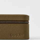 A close-up of the textured taupe leather Fraser 3 Watch Case with the brand name "TAWBURY" embossed on the lower front.