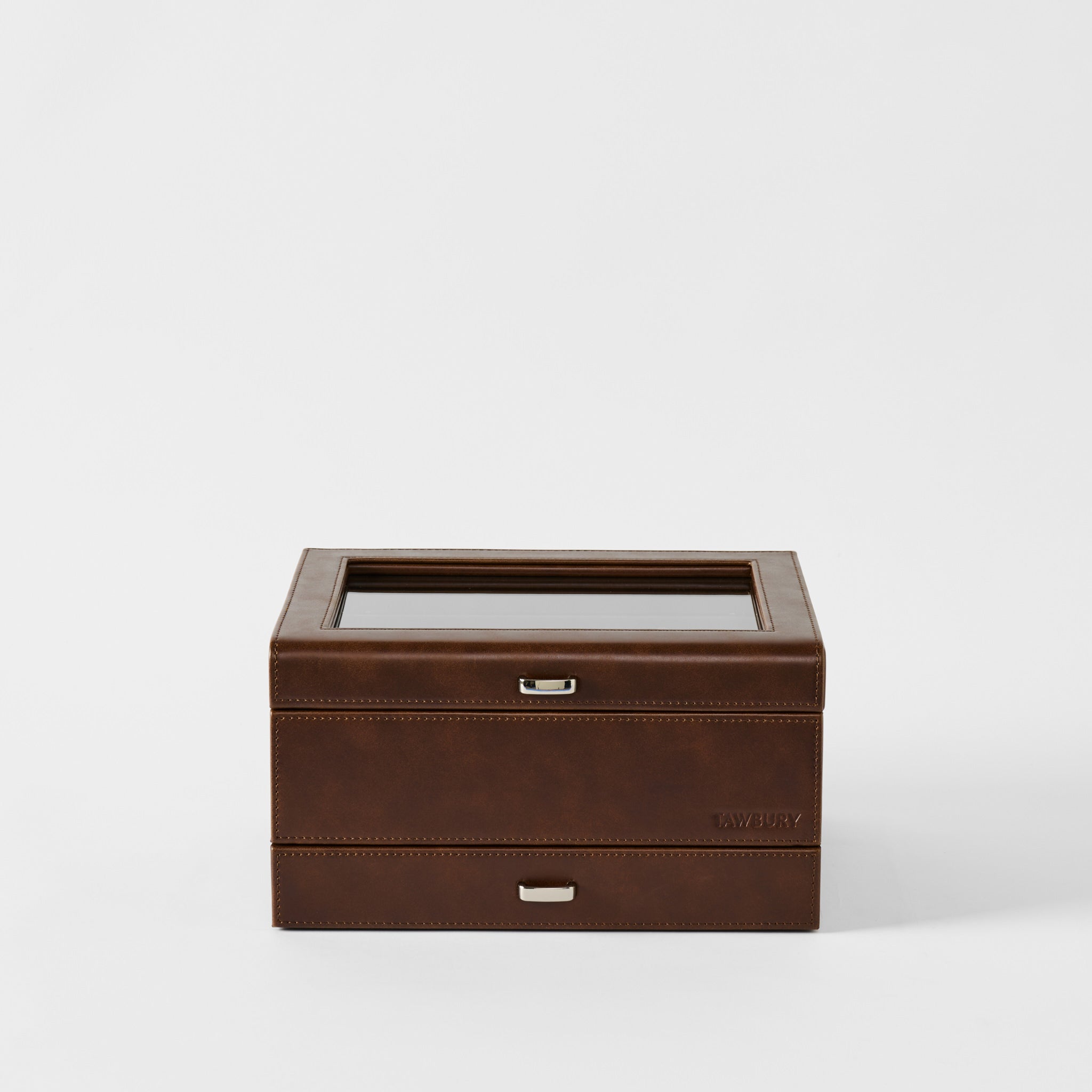 The TAWBURY Bayswater 8 Slot Watch Box with Storage in chestnut brown faux leather, featuring visible stitching, a glass top, and metal handles, is embossed with "TAWBURY" and shown against a white background.