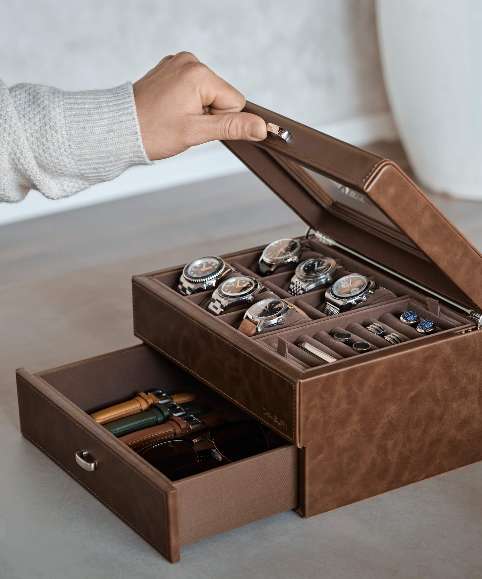 A watch enthusiast holding a TAWBURY Bayswater 6 Watch Jewellery Box - Brown made with vegan leather, containing watches.