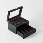 TAWBURY Bayswater 6 Watch Jewelry Box in Midnight Black features a glass lid, multiple ring slots, top compartments, and an open drawer with divided sections—all crafted in stylish faux leather against a plain background.