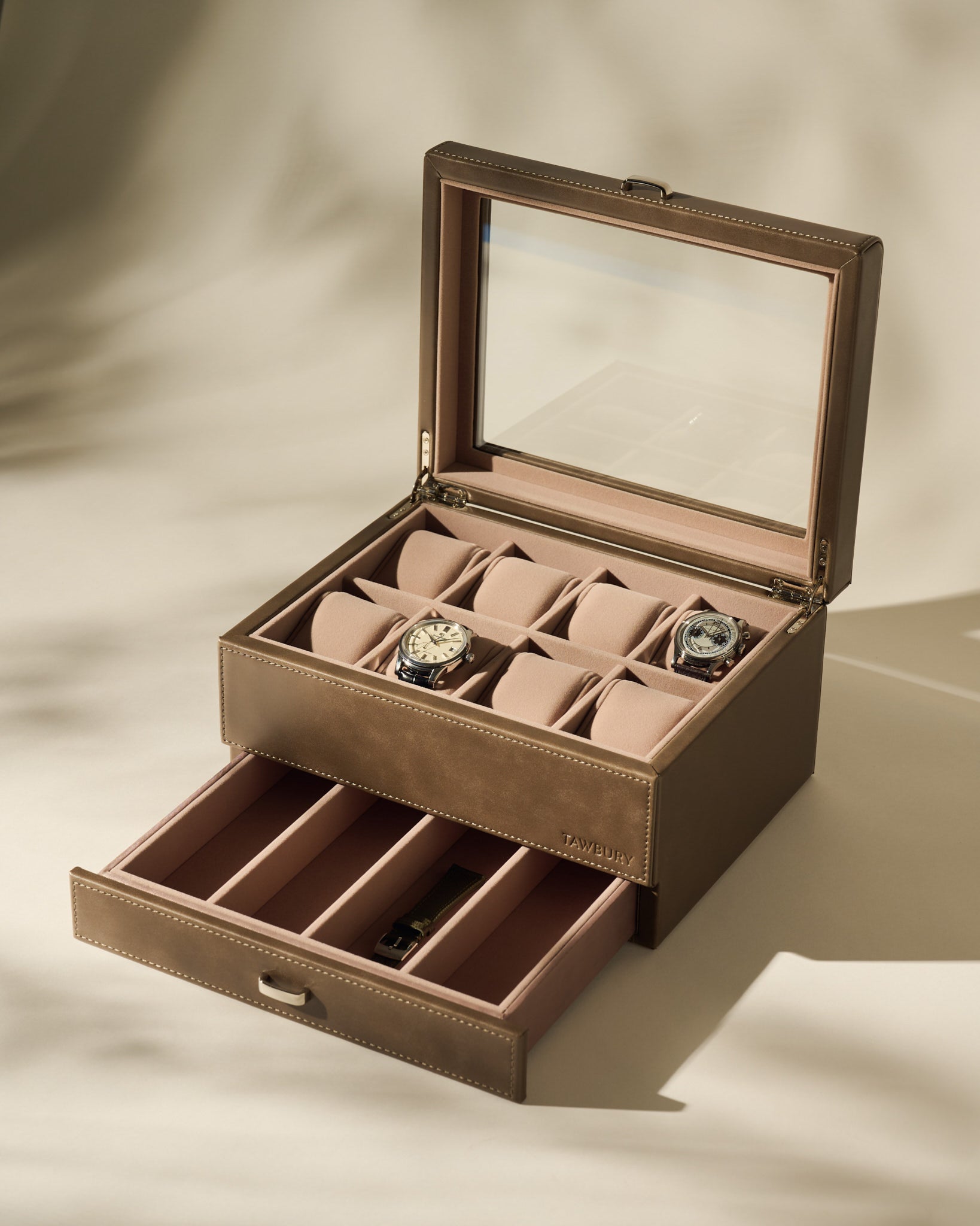The TAWBURY Bayswater 8 Slot Watch Box with Storage in taupe features a glass lid, pillows for two watches, multiple empty compartments, and a lower drawer for extra watch storage.