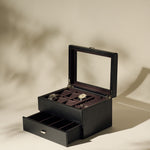 The TAWBURY Bayswater 6 Watch Jewelry Box in Black/Charcoal features a glass lid and an open display with two watches in separate compartments, plus a lower drawer with additional empty storage sections.