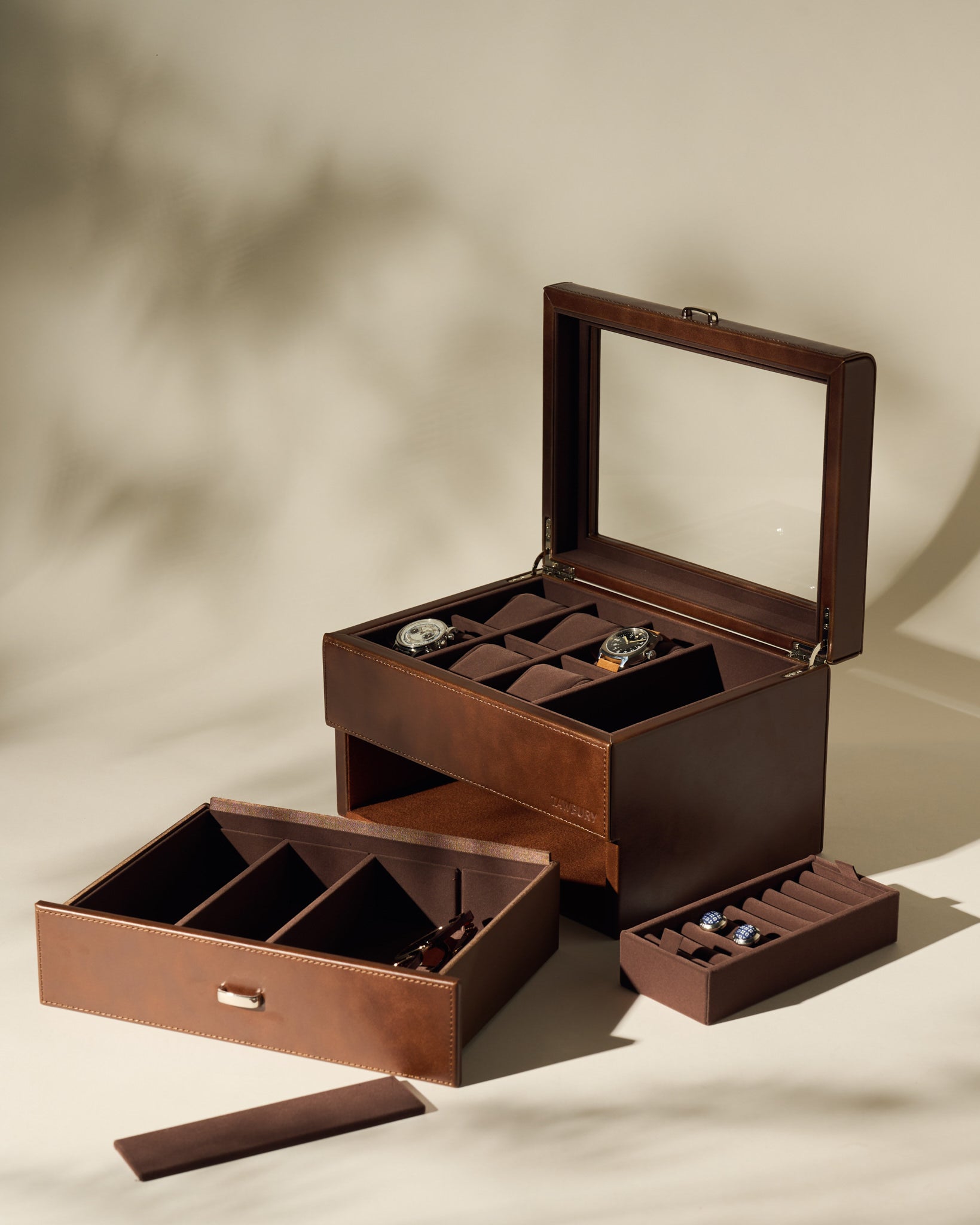 The TAWBURY Bayswater 6 Watch Jewelry Box in brown is shown open on a neutral background. This elegant case features compartments and removable trays, holding up to six watches and several cufflinks inside.