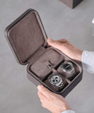 A person holding two watches in TAWBURY Fraser 2 Watch Travel Case with Storage - Brown.