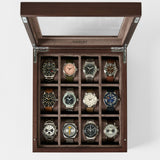 The TAWBURY Grove 12 Slot Wooden Watch Box in dark walnut features a glass lid and displays twelve wristwatches in individual compartments—perfect for collectors and shown from a top-down view.