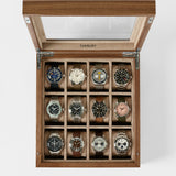 The TAWBURY Grove 12 Slot Wooden Watch Box in light walnut wood features a glass lid, elegantly displaying twelve wristwatches in separate compartments for stylish storage.