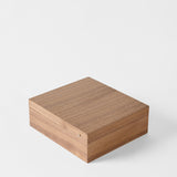 The TAWBURY Grove 12 Slot Wooden Watch Box features a classic walnut wood design with a closed lid, smooth finish, and subtle brass detail, presented against a plain white background.