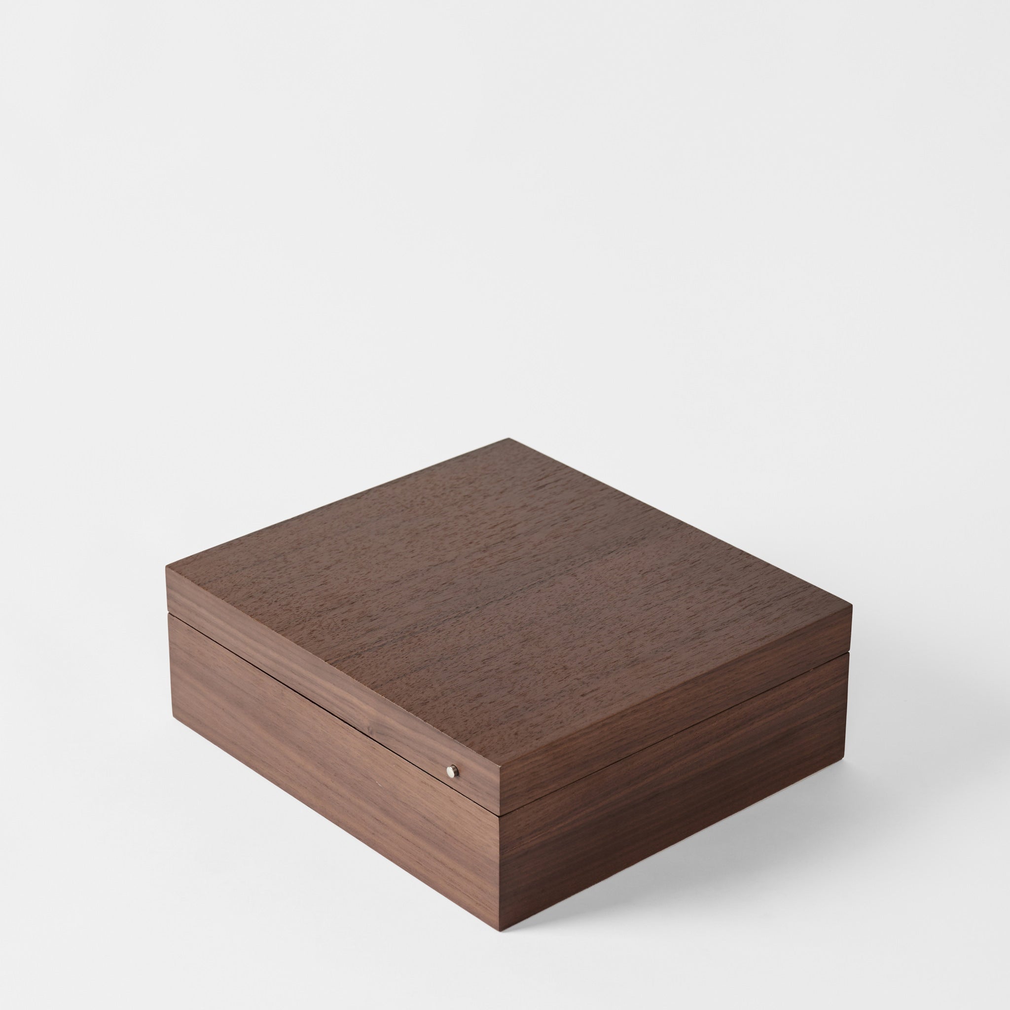 The TAWBURY Grove 12 Slot Wooden Watch Box in dark walnut wood, featuring a closed lid and smooth veneer finish, sits against a plain white background.