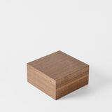 A closed TAWBURY Grove 6 Slot Wooden Watch Box in Classic Walnut Wood, featuring a smooth finish, sits on a plain white background, highlighting the elegance of premium wooden watch boxes.